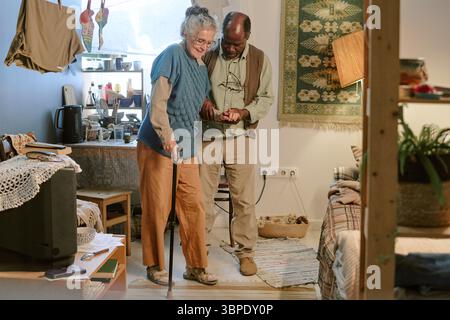 Femme caucasienne senior et homme noir senior debout ensemble à l'intérieur souriant Banque D'Images
