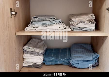 Le linge de lit, les draps, les taies d'oreiller et les serviettes sont soigneusement empilés dans le placard de la chambre Banque D'Images