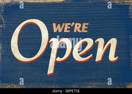 L'enseigne plate en bois « We're Open » est visible sur fond de planche bleue altérée avec de la peinture écaillée Banque D'Images