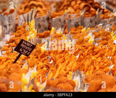 Gros plan de frites de patates douces croustillantes dans des cônes de papier à vendre sur un stand alimentaire au marché de la Boqueria, Barcelone, Espagne. Banque D'Images