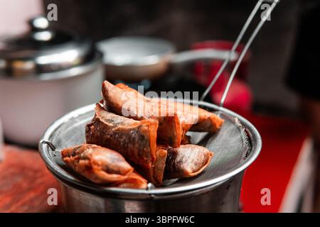 Rouleaux de printemps dorés croustillants égouttant l'huile sur une passoire en métal dans un cadre de cuisine maison. Parfait pour les thèmes culinaires, asiatiques ou culinaires. Banque D'Images