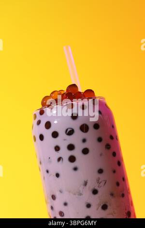 Thé à bulles de lait savoureux en verre sur fond jaune, gros plan Banque D'Images