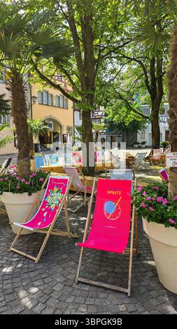 Un endroit libre pour se détendre avec des chaises de plage et du géranium français rose dans la ville médiévale, sous les palmiers et les platanes. Format vertical. 05 mai 2025. Uber Banque D'Images