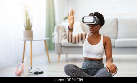 Femme de fitness africaine portant des lunettes VR expérimentant la réalité augmentée en intérieur Banque D'Images
