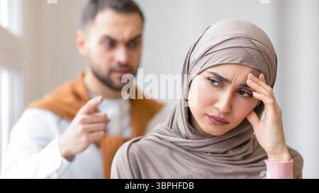 Un mari musulman agressif criait devant une femme déprimée debout à la maison Banque D'Images