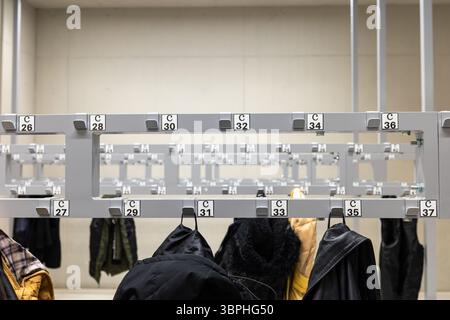 Manteaux et vestes suspendus dans le vestiaire. Photo prise à la lumière artificielle dans un bâtiment d'utilité publique Banque D'Images