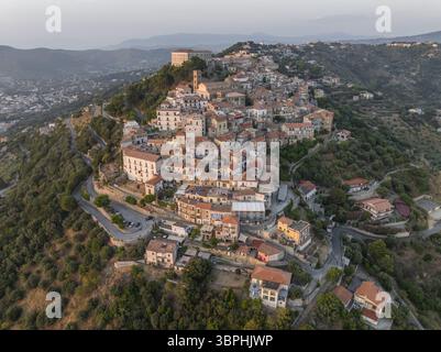 Vue aérienne d'une ville perchée dans la lumière dorée, avec des toits en terre cuite contrastant avec le vert profond des arbres environnants, Santa Maria Banque D'Images