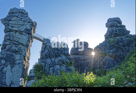 Le soleil du matin brille à travers une ouverture dans l'Externsteine. L'Externsteine, une formation rocheuse de grès d'environ 40 mètres de haut dans le Teutoburg for Banque D'Images