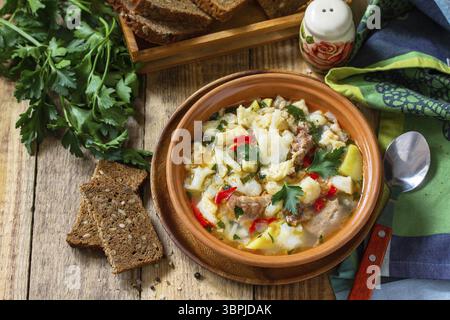 Soupe épaisse hongroise traditionnelle avec du bœuf, des légumes et des boulettes sur une table en bois. Dîner ou déjeuner chaud Banque D'Images