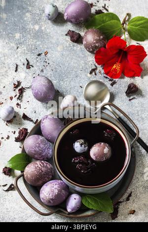 Colorant naturel d'oeuf de Pâques violet. Les oeufs faits maison sont peints avec un colorant naturel à base d'oeufs de fleurs d'hibiscus séchées sur un dessus de table en pierre grise. Copier l'espace Banque D'Images