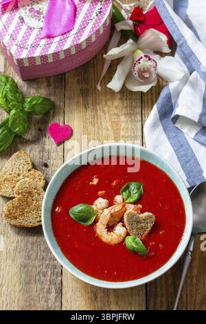 Soupe de Saint-Valentin maison, cuisine festive. Gazpacho de purée de soupe de tomates avec tomates servies fruits de mer sur une table en bois rustique Banque D'Images