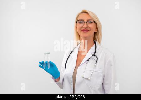 Femme d'âge moyen dans un manteau médical blanc et des gants tenant deux tubes à essai pour la recherche en laboratoire. Porter un stéthoscope. Isolé sur fond blanc. Banque D'Images