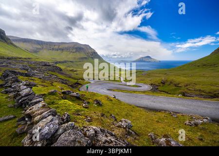 Vue d'une route sinueuse menant à l'île de Koltur en arrière-plan. Streymoy, Torshavnar district, Îles Féroé, Danemark, Scandinavie. Banque D'Images