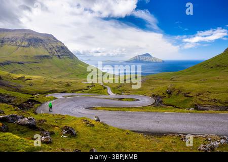 Vue d'une route sinueuse menant à l'île de Koltur en arrière-plan. Streymoy, Torshavnar district, Îles Féroé, Danemark, Scandinavie. Banque D'Images