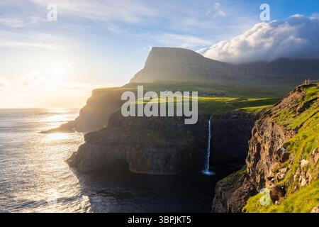 Vue sur la cascade de Mulafossur avec le petit village de Gasadalur. Île de Vagar, Îles Féroé, Danemark, Europe. Banque D'Images
