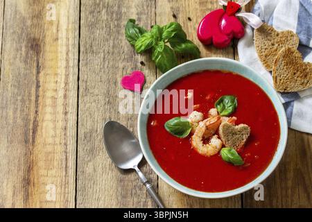 Soupe de Saint-Valentin maison, cuisine festive. Gazpacho de purée de soupe de tomates avec tomates servies fruits de mer sur une table en bois rustique. Copier l'espace Banque D'Images