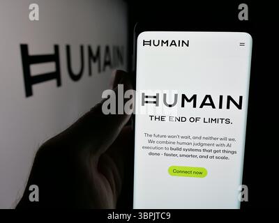 Dans cette illustration photo, une personne tient un smartphone avec la page Web de la société saoudienne d'intelligence artificielle humain sur l'écran devant le logo. Banque D'Images