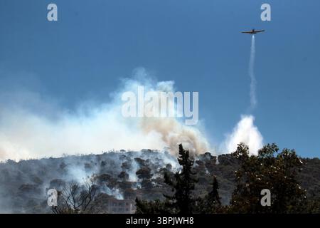 Un avion de lutte contre les incendies jette de l'eau alors qu'un feu de forêt brûle à Aghios Dimitrios à l'est d'Athènes. Banque D'Images