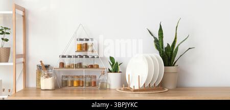 Étagères avec différentes épices, plats et plantes sur le comptoir près du mur léger dans la cuisine Banque D'Images