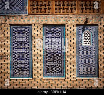 Vue rapprochée d'un mur décoratif présentant des carreaux bleus complexes et des motifs géométriques. Le mur présente trois conceptions de fenêtres distinctes, chacune Banque D'Images