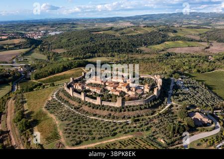 Vue aérienne de la ville médiévale fortifiée se prélasser dans la lumière chaude du soleil, entouré d'oliviers et de collines toscanes vallonnées, une tapisserie de vert et d'or, M. Banque D'Images