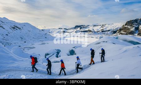 Groupe de randonneurs traversant le glacier Sólheimajökull couvert de neige pendant l'hiver, sud de l'Islande Banque D'Images