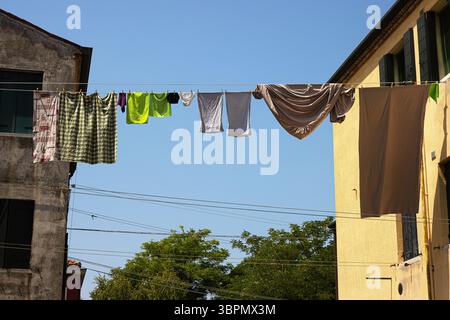 Séchage coloré du linge sur les lignes de tissu de manière italienne traditionnelle. Des cordes tendues entre de vieux bâtiments sous un ciel bleu clair par une journée ensoleillée à Mura Banque D'Images