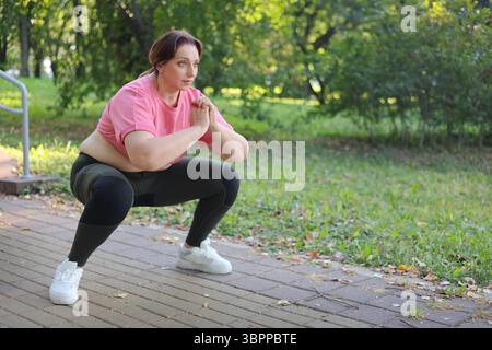 Femme de fitness âgée faisant des squats dans le parc Banque D'Images