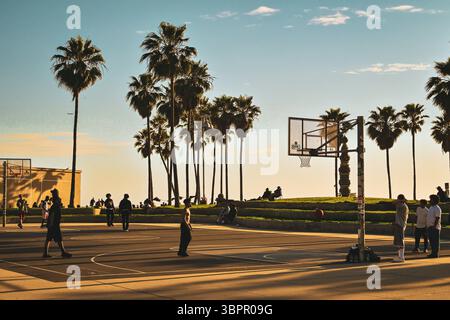 Les gens jouant au basket sur un terrain extérieur à Venice Beach au coucher du soleil, Los Angeles, Californie, États-Unis Banque D'Images