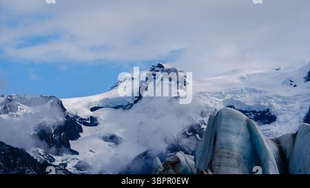 Explorez l'époustouflant glacier Svinafellsjokull, une superbe formation de glace sur fond de montagne spectaculaire en Islande. La glace scintillante contraste avec le ciel éclatant au-dessus. Banque D'Images