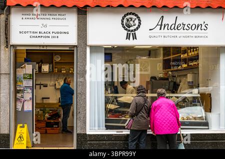 Femmes regardant dans une vitrine, Anderson's Butchers, North Berwick High Street, East Lothian, Écosse, Royaume-Uni Banque D'Images