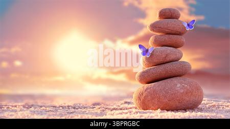 Tour en pierre. Galets naturels et papillon sur la plage. Équilibrer le corps, l'esprit, l'âme et l'esprit. Pratique de la santé mentale. Banque D'Images