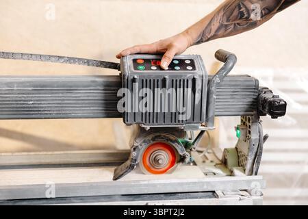 Ouvrier de la construction exploitant une scie de coupe de carrelage professionnelle, assurant des coupes précises pour un projet de rénovation domiciliaire Banque D'Images