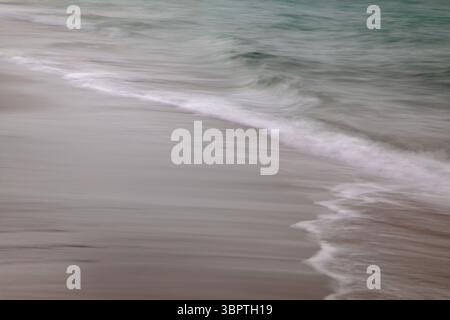 Dans la caméra flou de mouvement, vagues le long de la plage, vagues blanches océan vert mer, abstrait vertical Banque D'Images