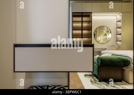 L'intérieur moderne de la chambre comprend une armoire flottante et une vue sur un coin lavabo chic, avec un miroir rond et des armoires encastrées éclairées. Banque D'Images
