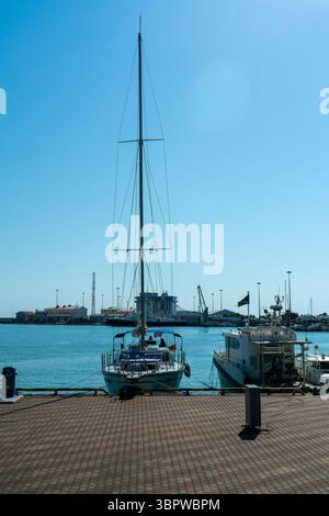 Petit yacht à voile avec voiles abaissées dans le port. Yacht privé dans le port maritime sur l'eau. Banque D'Images