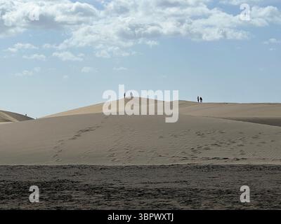 Vue panoramique des gens explorant de vastes dunes de sable sous un ciel lumineux. Dunes de Maspalomas, îles Canaries Banque D'Images