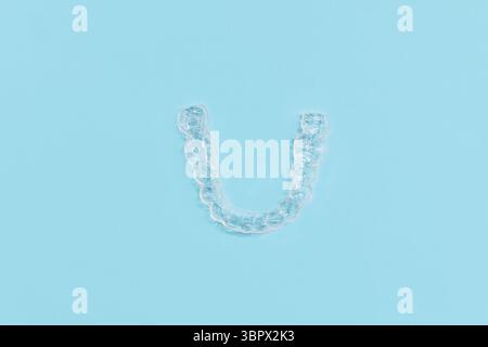 Vue de dessus de dents dentaires transparentes personnalisées protège-morsures aligners clairs pour la mâchoire inférieure sur fond bleu Banque D'Images