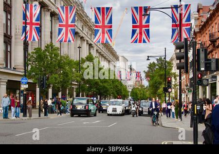 Arbre bordé Oxford Street avec des drapeaux suspendus Union Jack taxis touristes et la circulation avec Selfridges grand magasin Londres Angleterre Royaume-Uni Banque D'Images