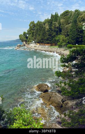Une belle scène côtière avec des eaux turquoises claires, des rivages rocheux et des arbres verdoyants sous un ciel lumineux Banque D'Images