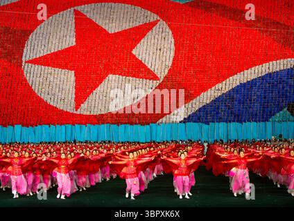 Des femmes dansent devant le drapeau géant nord-coréen pendant l'Arirang, DGC, Pyongyang, Corée du Nord Banque D'Images