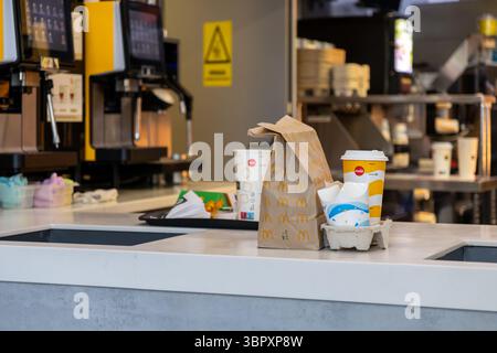 Poznan, Pologne - 18 juin 2025 : un repas McDonald's à emporter avec un sac en papier et des gobelets de marque, y compris Coca-Cola, sur un comptoir de service propre Banque D'Images