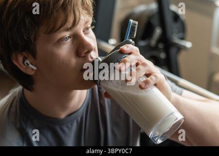 Gros plan d'un culturiste ou d'un homme buvant un shaker de protéines au centre de fitness. Entraînement musculaire au gymnase. Fitness concept de style de vie sain. Supplément Banque D'Images