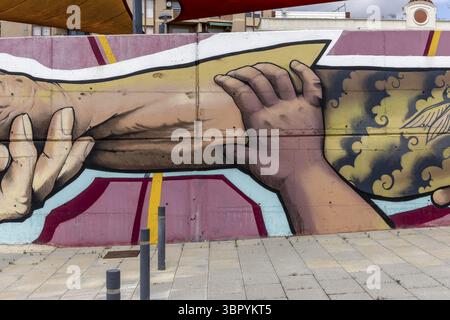 Grand graffiti long de mains de différentes couleurs de peau serrant la main sur un mur de béton à Carrer Primer de Maig, Montmelo, Barcelona, Barcelona prov Banque D'Images