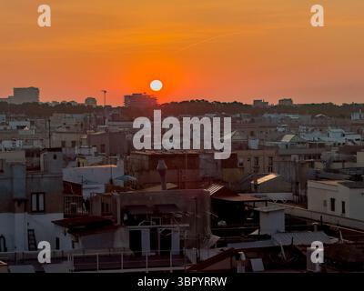 Un beau lever de soleil orange brumeux sur les toits de Barcelone, en Espagne, créant une vue chaleureuse et atmosphérique sur la ville. Banque D'Images