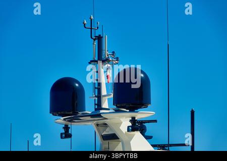 Équipement de communication maritime moderne avec antennes contre un ciel bleu clair Banque D'Images