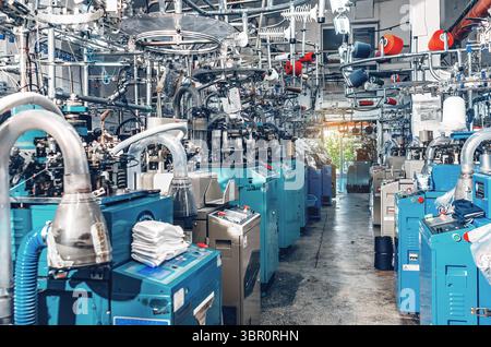 Vue industrielle des machines à tricoter de chaussettes modernes au travail dans l'usine textile. Production industrielle de chaussettes Banque D'Images