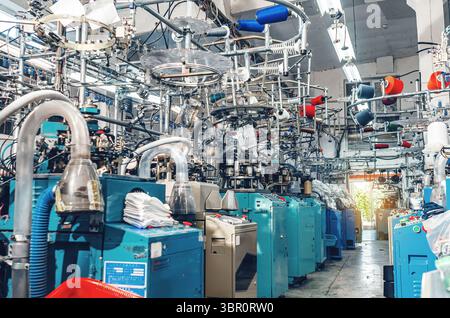 Vue industrielle des machines à tricoter de chaussettes modernes au travail dans l'usine textile. Production industrielle de chaussettes Banque D'Images