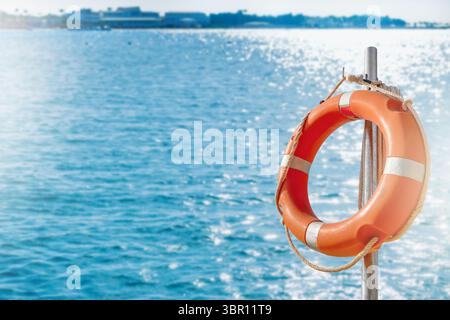 Cercle de bouées de sauvetage. Vue panoramique de bouée de sauvetage rouge et blanche sur le poteau sur la plage de bord de mer. Paysage de paysage de la rive de l'océan de mer le jour ensoleillé. Sauvetage en eau Banque D'Images