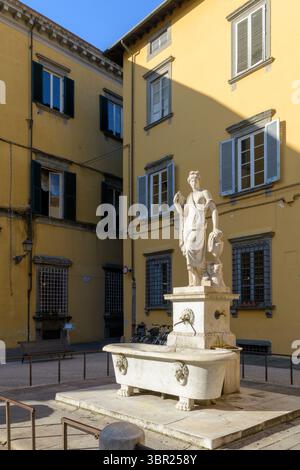 Fontaine en marbre avec figure féminine dans la cour, Lucques, Italie, sculpture néoclassique du XIXe siècle, architecture de la ville historique en arrière-plan. Banque D'Images